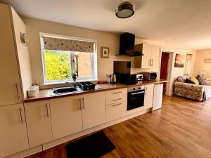 a kitchen with white cabinets and a window at The Old Gate House Annexe in Alford