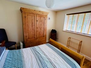 a bedroom with a bed and a wooden cabinet at The Old Gate House Annexe in Alford