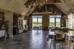 a dining room with tables and chairs and windows at Fantastic Holiday Property Kragelund For Up To 24 Guests! in Åbybro