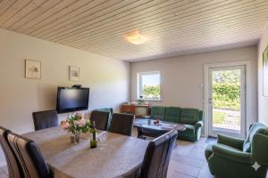 a dining room with a table and chairs and a television at Fantastic Holiday Property Kragelund For Up To 24 Guests! in Åbybro