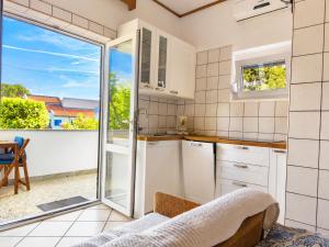 a kitchen with white cabinets and a sliding glass door at Apartments Pika in Krk +51 photos