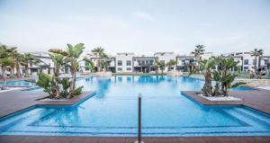 une grande piscine avec des palmiers et des bâtiments dans l'établissement Oasis beach, à Playas de Orihuela 2 autres photos