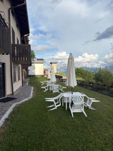 a row of white chairs and umbrellas on the grass at Appartamento alla Lupa in Vetriola