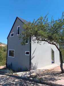 a white building with a tree in front of it at Chalé Punaras in Araruna