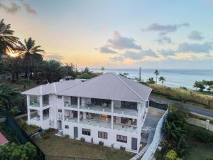 an aerial view of a white building with the ocean at Cove Holiday Apartments in Bel Ombre
