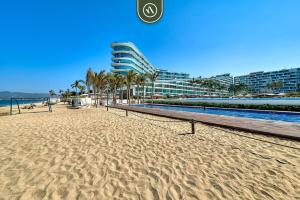 a sandy beach with palm trees and a building at Ocean view 2BR Condo - Private Terrace - Beach in Nuevo Vallarta