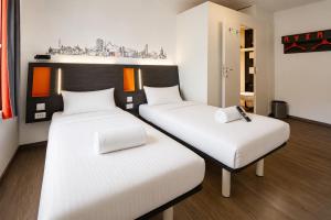 two beds in a room with white sheets at easyHotel Zürich City Limmatplatz in Zurich
