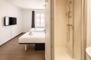 a small room with a bed and a shower at easyHotel Zürich City Limmatplatz in Zurich +36 photos