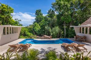 a patio with chairs and a swimming pool at Ikana Puerto Aventuras Golf Getaway in Puerto Aventuras
