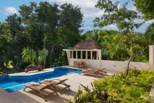 a resort pool with chairs and a gazebo at Ikana Puerto Aventuras Golf Getaway in Puerto Aventuras