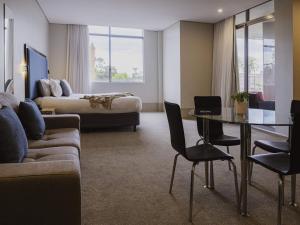 a hotel room with a couch and a bed and a table at Mercure Centro Port Macquarie in Port Macquarie
