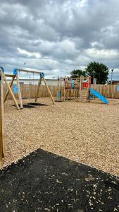a playground with two swings and a slide at B by the sea in Scratby