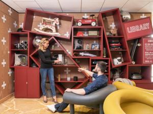 a man and a woman in a room with a shelf at Aparthotel Adagio Val d'Europe près de Disneyland Paris in Serris