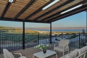 a patio with white chairs and a view of the water at וילה מארי עם בריכה במגדל in Migdal