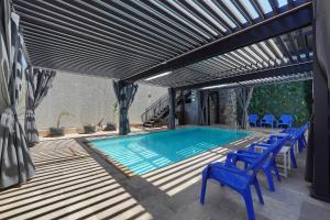 a swimming pool with blue chairs next to a building at וילה מארי עם בריכה במגדל in Migdal