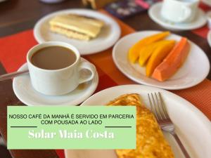 a table with plates of food and a cup of coffee at El Shaday Suítes - ATÍNS in Atins