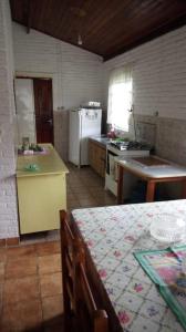 a kitchen with a table and a kitchen with a refrigerator at Chácara Pousada in Juquitiba
