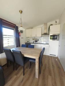 a kitchen and dining room with a wooden table and chairs at De Blenck 69 in Callantsoog