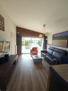 a living room with a black couch and a television at De Blenck 69 in Callantsoog
