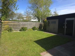 a yard with a fence and a house at De Blenck 69 in Callantsoog