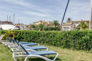 a row of chaise lounge chairs sitting in the grass at Art- Apartamentos Revilla Tacke E in Empuriabrava