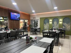 a restaurant with tables and chairs and a flat screen tv at Hotel Maioris Kumate Culiacán in Culiacán
