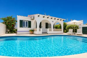 a villa with a swimming pool in front of a house at Villa Emilio in Cala en Porter