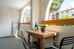 a table and chairs on a balcony with a bottle of wine at Appartement Cool Montagne in Briançon