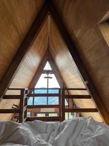 ein Bett in einem Zimmer mit einem großen Fenster in der Unterkunft Wildcabinpanoramic Marisel in Mărişel