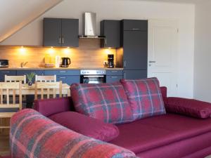 a living room with a purple couch and a kitchen at Kraatzer Ferienwohnungen in Gransee