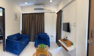 a living room with two blue chairs and a tv at Auravista in Pālghar