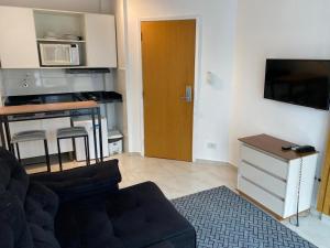 a living room with a couch and a kitchen at Atlantico Flat Santos in Santos