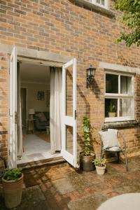 an open door to a brick building with a chair and a window at Central Village Cottage, The Corders in Moreton in Marsh