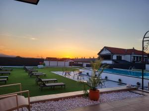 a resort with a pool and tables and chairs at sunset at Diamona Lux Spa Apartman in Niš
