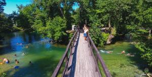 a woman standing on a bridge over a body of water at Una Relax Apartment - Naturally Cool - North-Facing - Near the River in Bosanska Krupa