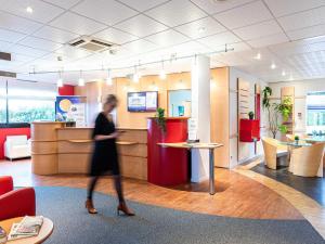 a woman walking through a lobby of a store at ibis Quimperle in Quimperlé