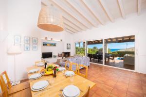 a dining room and living room with a table and chairs at Villa Binipaco in Binibeca