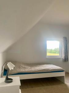 a white bedroom with a bed with a window at Domek Adam in Macharce
