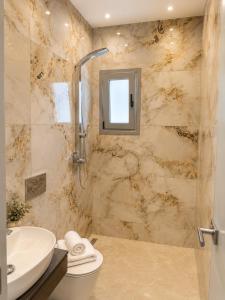 a bathroom with a sink and a toilet and a shower at Maxa Residences - Free Airport Shuttle in Artemida
