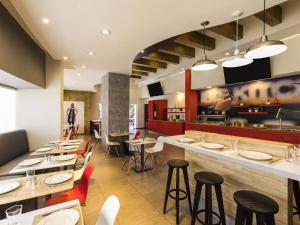 a restaurant with tables and chairs and a bar at Ibis Chihuahua in Chihuahua