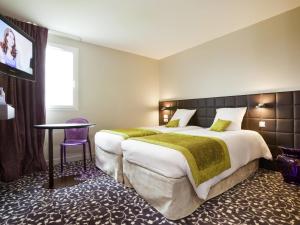 a hotel room with a large bed and a table at ibis Styles Compiegne in Jaux