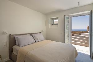 a bedroom with a bed and a sliding glass door at Serene Shore Serifos in Alona