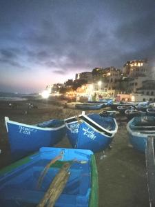a group of boats sitting on the beach at night at Waves Surf House in Taghazout