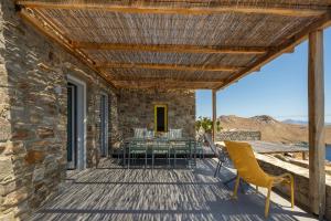 a wooden deck with a table and chairs on it at Serene Shore Serifos in Alona