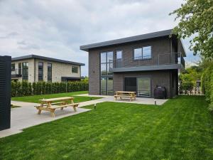 a house with two benches in the grass at Villa Aurelia Spa, Zeewolde 52 in Zeewolde