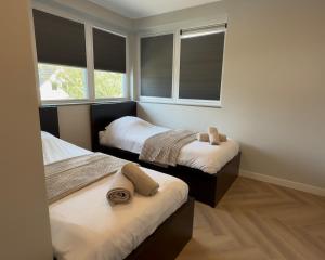 a bedroom with two beds and two windows at Villa Aurelia Spa, Zeewolde 52 in Zeewolde +66 photos