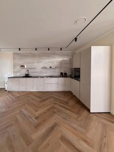 a kitchen with a wooden floor and white cabinets at Villa Aurelia Spa, Zeewolde 51 in Zeewolde