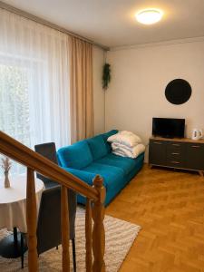 a living room with a blue couch in front of a window at Amphora Kompleks Wypoczynkowy in Krynica Zdrój