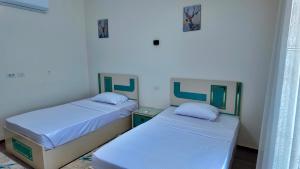 two beds in a room with white walls at Grand Stylish Two bedrooms Apartment in El Alamein