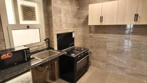 a small kitchen with a stove and a sink at Grand Stylish Two bedrooms Apartment in El Alamein